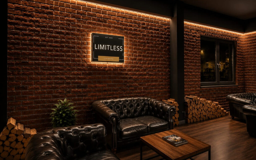 Lounge Eingang Limitless Sports Recklinghausen Lounge mit beleuchtetem Limitless Sports Logo, Chesterfield Sofas und Backsteinwand in Recklinghausen
